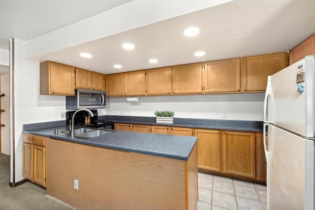 kitchen with recessed lighting, dark countertops, a sink, stainless steel microwave, and freestanding refrigerator