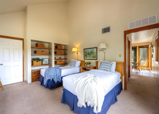 bedroom with a towering ceiling, visible vents, and light colored carpet
