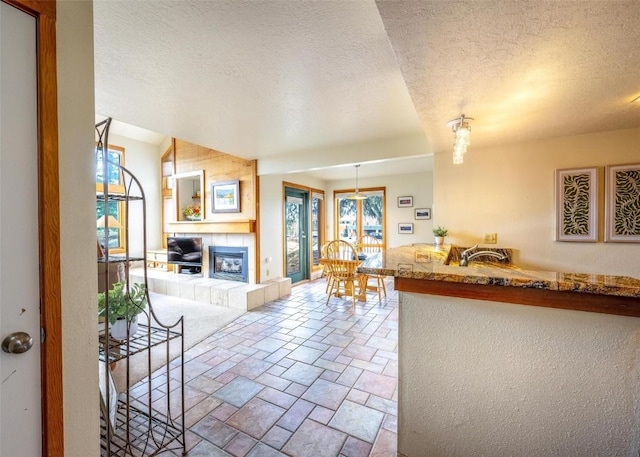living room featuring a textured ceiling, a tile fireplace, and stone tile flooring