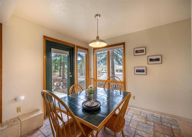 dining area with a wealth of natural light, a textured ceiling, and stone tile floors