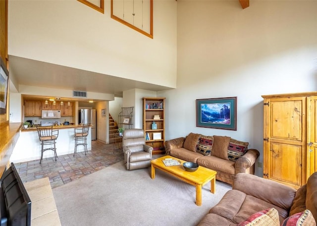 living room with visible vents, stairs, and a high ceiling