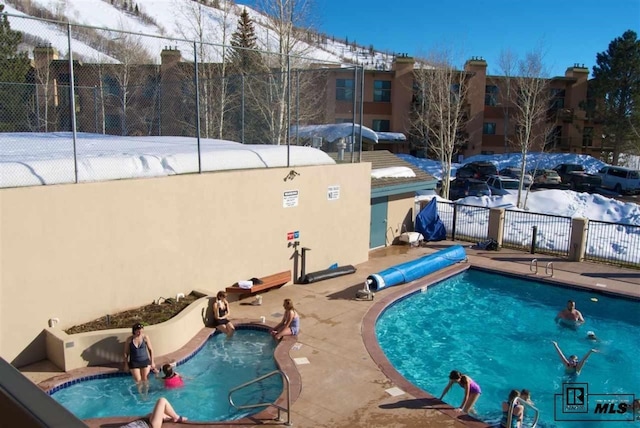 snow covered pool with a community pool, a patio area, and fence