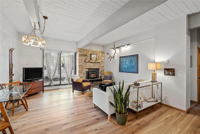 living area with light wood finished floors, baseboards, an inviting chandelier, beamed ceiling, and a wood stove