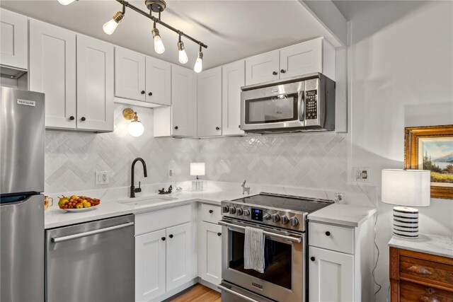 kitchen with white cabinetry, tasteful backsplash, stainless steel appliances, and a sink