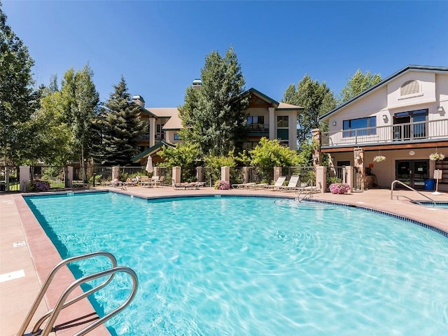 community pool with a patio area and fence
