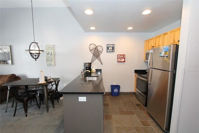 172 Copper Cir Unit 101, Copper Mountain, CO 80443 - kitchen with light brown cabinetry, dark countertops, a sink, a peninsula, and appliances with stainless steel finishes