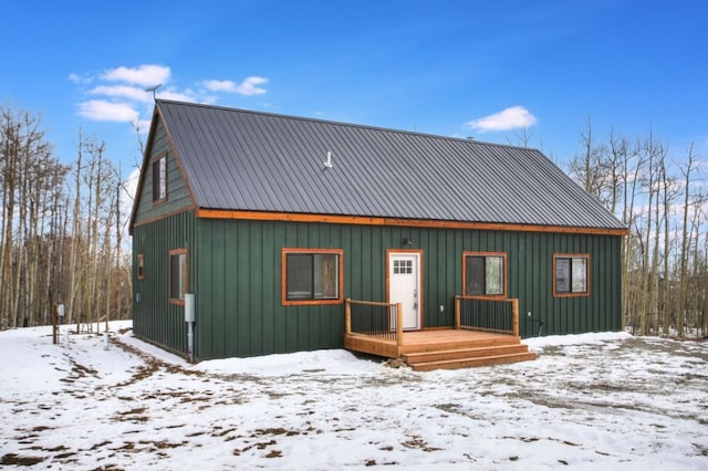 snow covered rear of property featuring board and batten siding and metal roof