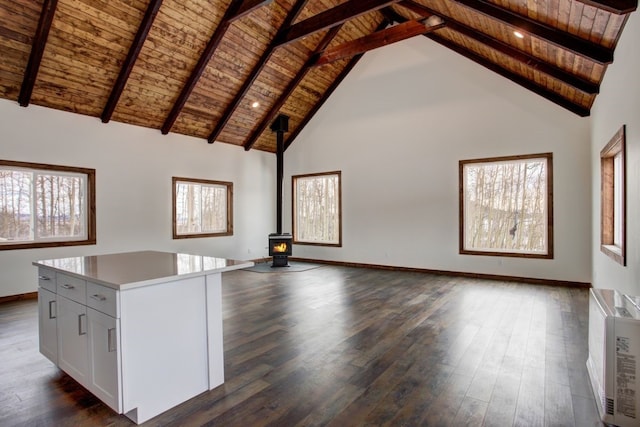 unfurnished living room with high vaulted ceiling, wood ceiling, a wood stove, beam ceiling, and dark wood-style floors
