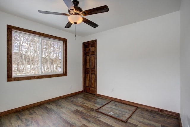 spare room with wood finished floors, a ceiling fan, and baseboards