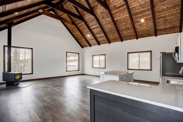 unfurnished living room featuring dark wood-style floors, a wealth of natural light, wood ceiling, high vaulted ceiling, and a wood stove