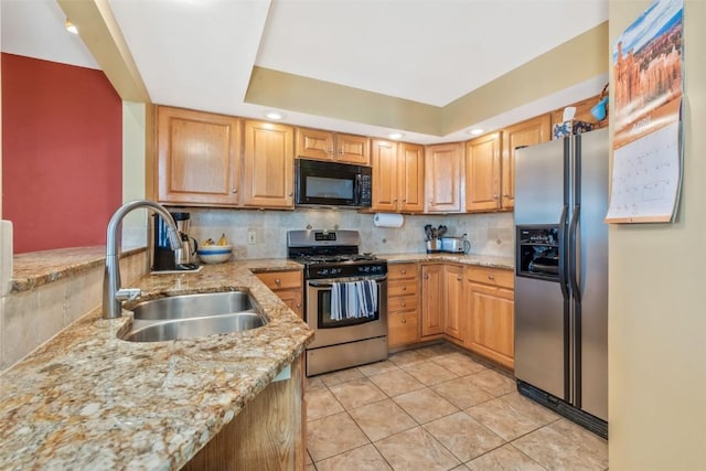 kitchen with backsplash, appliances with stainless steel finishes, light stone countertops, a sink, and light tile patterned floors