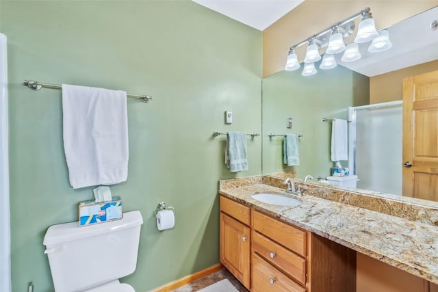 bathroom with toilet, baseboards, a shower stall, and vanity