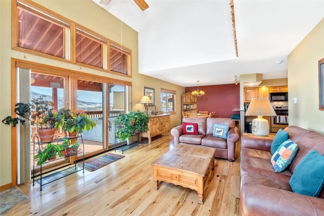 living room featuring light wood finished floors and ceiling fan with notable chandelier