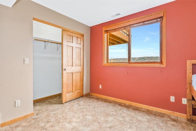 unfurnished bedroom with visible vents, baseboards, and a closet