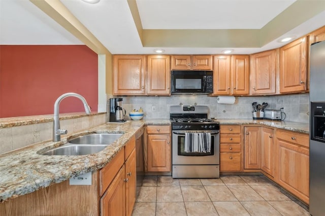 kitchen featuring light stone countertops, tasteful backsplash, a sink, appliances with stainless steel finishes, and light tile patterned floors