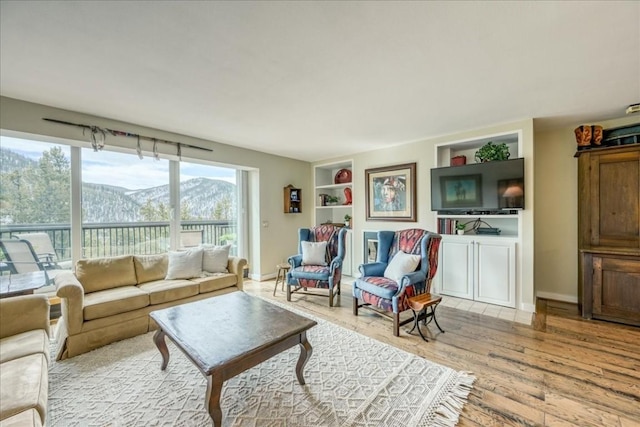 living room featuring baseboards, light wood-style floors, and built in shelves