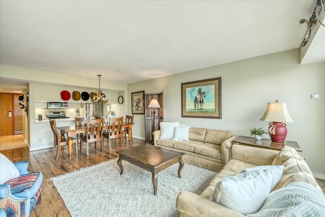 living room with baseboards, a chandelier, and wood finished floors