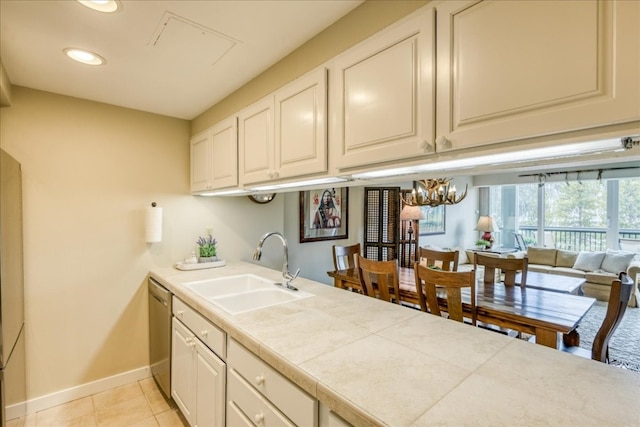 kitchen with stainless steel dishwasher, a sink, baseboards, recessed lighting, and a notable chandelier