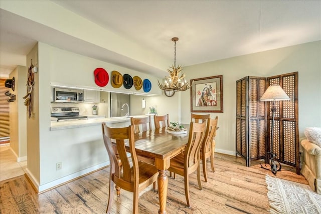 dining room with an inviting chandelier, light wood finished floors, and baseboards