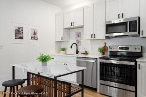790 Tucker St Unit 790, Craig, CO 81625 - kitchen featuring appliances with stainless steel finishes, light countertops, white cabinets, and light wood-type flooring