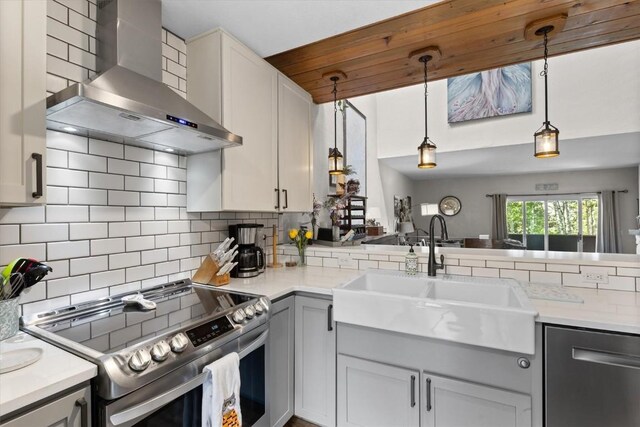 2146 Aster Pl Unit 3, Steamboat Springs, CO 80487 - kitchen featuring wall chimney range hood, stainless steel appliances, a sink, backsplash, and hanging light fixtures