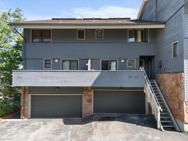 2146 Aster Pl Unit 3, Steamboat Springs, CO 80487 - rear view of property with an attached garage, driveway, stone siding, and stairway