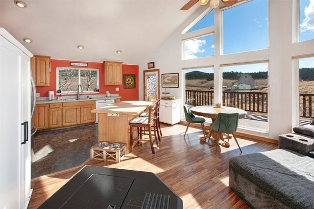 kitchen with high vaulted ceiling, white refrigerator, a sink, light brown cabinetry, and light countertops