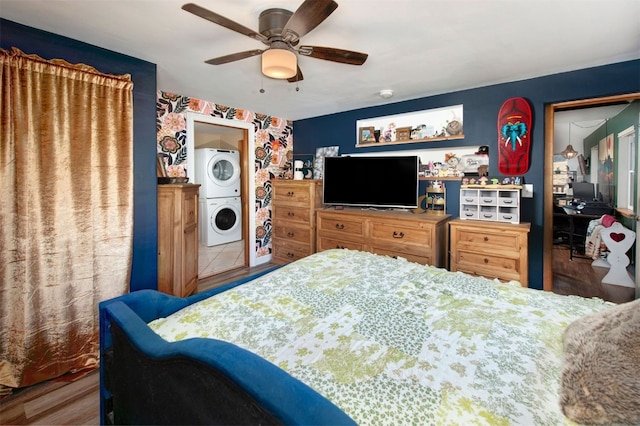 bedroom featuring stacked washing maching and dryer, ceiling fan, and wood finished floors