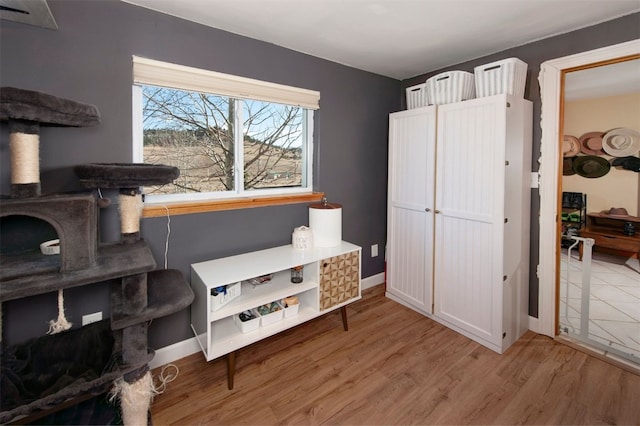 misc room featuring light wood-type flooring, baseboards, and a wood stove