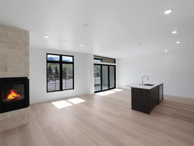 740 Blue River Pkwy Unit A22, Silverthorne, CO 80498 - unfurnished living room with light wood-style flooring, a fireplace, a sink, baseboards, and recessed lighting