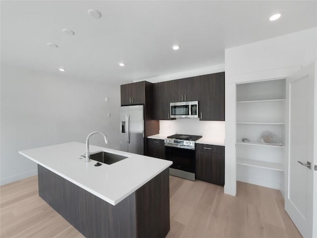 740 Blue River Pkwy Unit A22, Silverthorne, CO 80498 - kitchen featuring appliances with stainless steel finishes, a sink, light wood-style floors, a kitchen island with sink, and recessed lighting