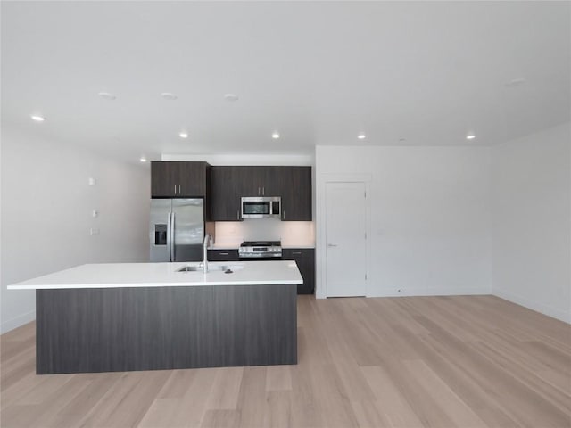 740 Blue River Pkwy Unit A22, Silverthorne, CO 80498 - kitchen featuring appliances with stainless steel finishes, a sink, light countertops, light wood-style floors, and a kitchen island with sink