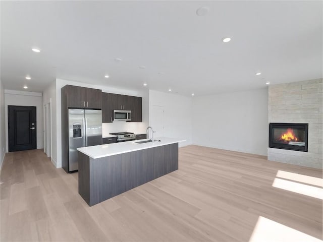 740 Blue River Pkwy Unit A22, Silverthorne, CO 80498 - kitchen featuring stainless steel appliances, a sink, light wood-style flooring, light countertops, and a center island with sink