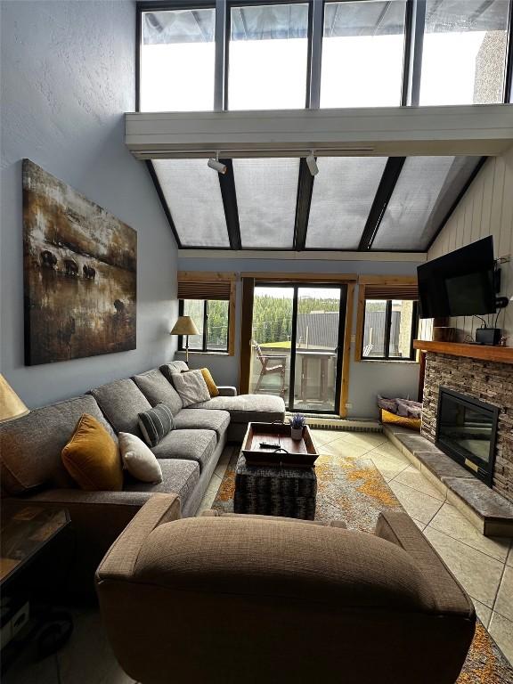 601 Village Rd # 501, Breckenridge, CO 80424 - living room with a stone fireplace, vaulted ceiling with beams, and tile patterned floors