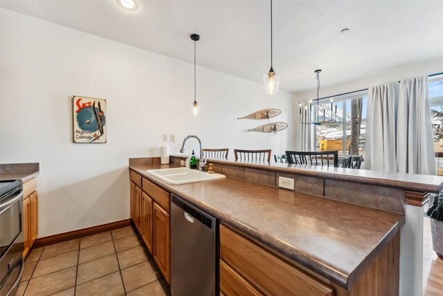 850 Blue River Pkwy Unit E5, Silverthorne, CO 80498 - kitchen with a peninsula, baseboards, brown cabinets, a sink, and stainless steel appliances