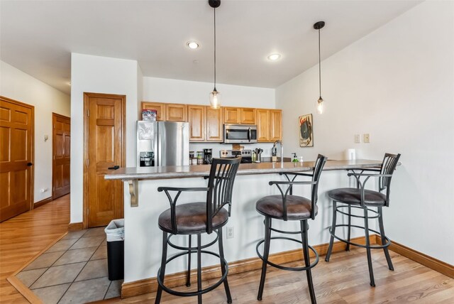 850 Blue River Pkwy Unit E5, Silverthorne, CO 80498 - kitchen featuring a breakfast bar area, light wood-type flooring, stainless steel appliances, and a peninsula