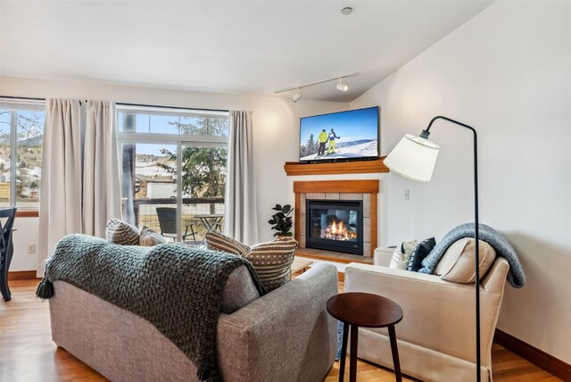 850 Blue River Pkwy Unit E5, Silverthorne, CO 80498 - living area featuring rail lighting, a tiled fireplace, wood finished floors, and a wealth of natural light