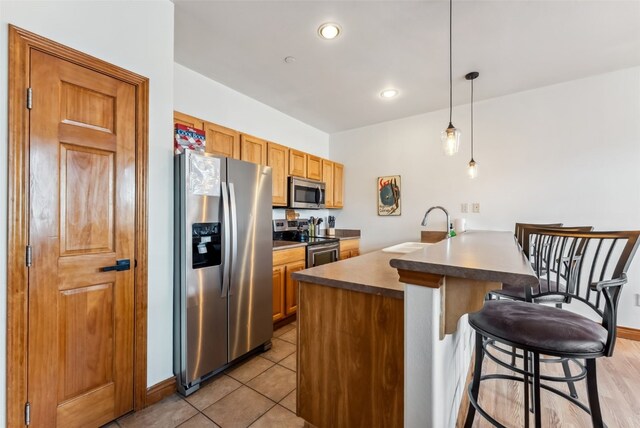 850 Blue River Pkwy Unit E5, Silverthorne, CO 80498 - kitchen with a kitchen breakfast bar, decorative light fixtures, appliances with stainless steel finishes, a sink, and a peninsula