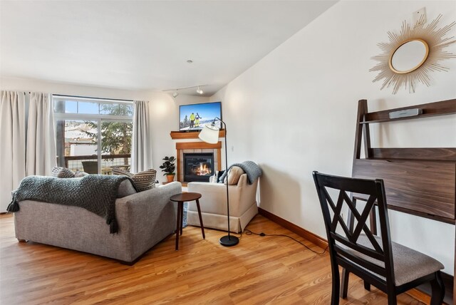 850 Blue River Pkwy Unit E5, Silverthorne, CO 80498 - living area with a glass covered fireplace, track lighting, baseboards, and light wood-type flooring