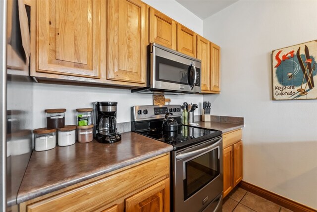 850 Blue River Pkwy Unit E5, Silverthorne, CO 80498 - kitchen with baseboards, dark countertops, appliances with stainless steel finishes, and tile patterned floors