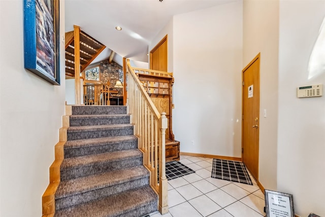 stairway with lofted ceiling, tile patterned flooring, and baseboards