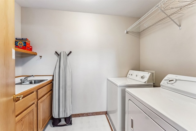 laundry room with a sink, light floors, cabinet space, baseboards, and independent washer and dryer