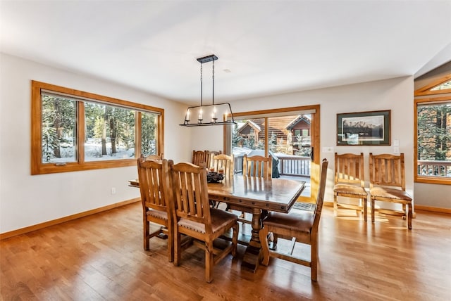 dining room featuring light wood finished floors, baseboards, and an inviting chandelier