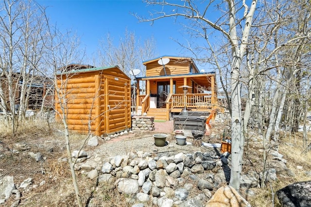 back of house with an outbuilding, a storage shed, and covered porch