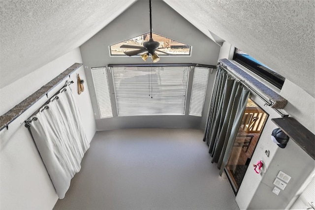 interior space featuring carpet, vaulted ceiling, a textured ceiling, and ceiling fan