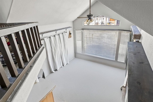interior space featuring a ceiling fan, carpet flooring, and vaulted ceiling