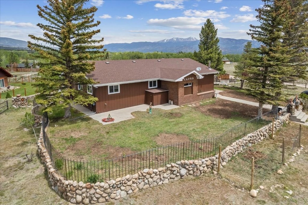 view of home's exterior featuring a fenced backyard, a yard, a mountain view, and a patio