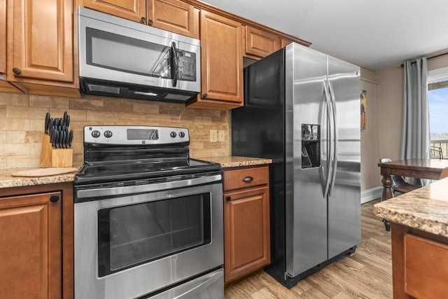 2626 Longthong Rd Unit 203, Steamboat Springs, CO 80487 - kitchen with light wood-style floors, stainless steel appliances, and brown cabinetry