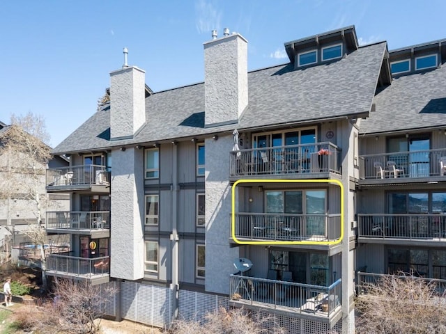2626 Longthong Rd Unit 203, Steamboat Springs, CO 80487 - rear view of property featuring a chimney, a shingled roof, and a balcony