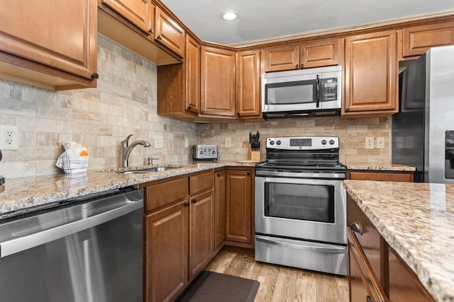 2626 Longthong Rd Unit 203, Steamboat Springs, CO 80487 - kitchen with light stone countertops, a sink, appliances with stainless steel finishes, and brown cabinetry